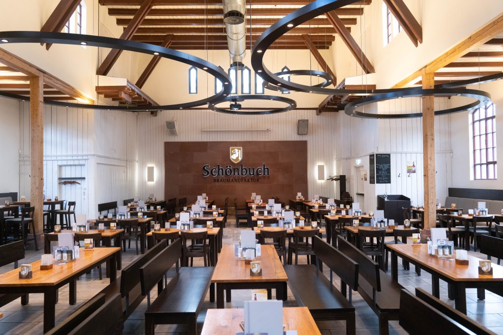 Sitzbereich im Brauhaus Schönbuch mit langen Tischen und moderner Lichtgestaltung.