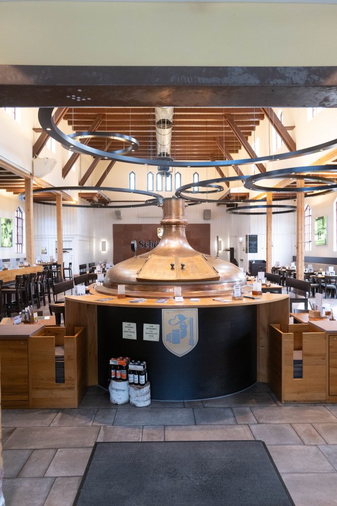 Großer Gastraum im Brauhaus Schönbuch mit zentraler Brauanlage und Sitzbereichen.