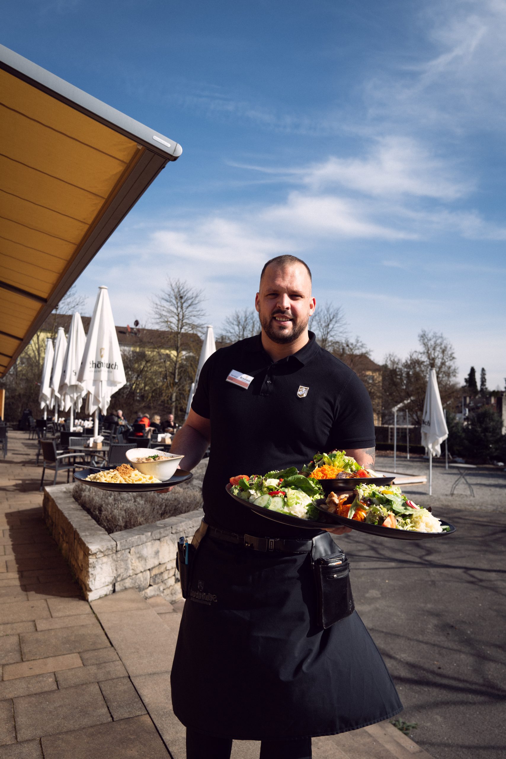 Mitarbeiter serviert einen frischen Salat auf der Terrasse des Brauhaus Schönbuch.
